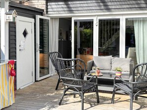 A covered patio with wicker furniture, a small table with drinks, and a sliding glass door leading to a balcony. - 4 Star Holiday Home in Knivsta (Knivsta)
