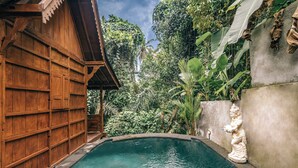 A wooden building with a pool, surrounded by lush greenery and a statue. - Ubud Dream Villa - Petulu (Ubud)