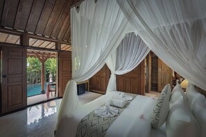 Ein Zimmer mit Bett, weißen Vorhängen und Blick auf ein Außenbecken.