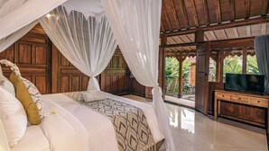 Un dormitorio con cama a dosel, paredes de madera, un televisor sobre un mueble de madera y vistas a la vegetación exterior.