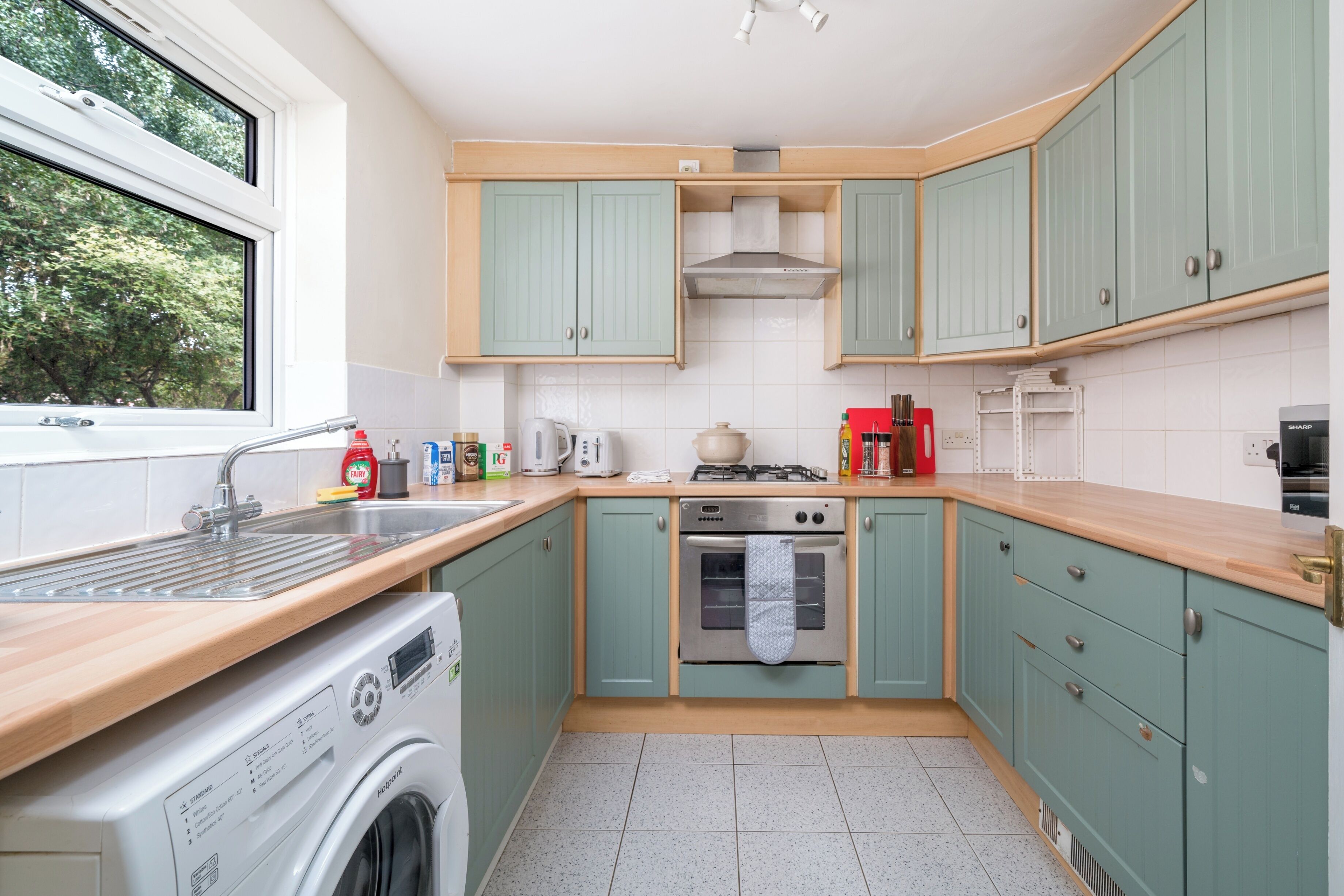 A compact kitchen with a washing machine, a stove, and a sink.