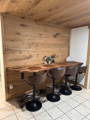Eine Holztresore mit einem Mittelteil-Waschbecken, vier Barhocker und einer kleinen Vogeldekoration an der Wand.