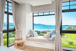 Ein Zimmer mit großem Fenster und Blick auf See und Berge.