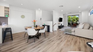 A modern living space with a dining area, a sofa, and a TV. - Loft & Levels @ Prospect - Contemporary Urban Living (Prospect)