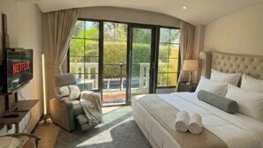 A modern hotel room with a large bed, a TV, a sofa, and a balcony with a view. - Direct pool access Studio - Venitian resort condo Jomtien beach Pattaya (Muang Pattaya)