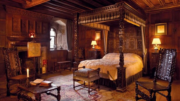 A traditional four-poster bed with a canopy, a fireplace, and ornate wooden furniture in a historic room. - Stud's Residency (Noida)