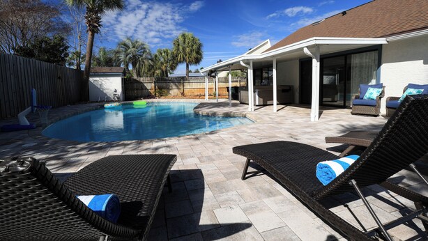 Ein Garten mit Schwimmbad, Liegestühlen und einer überdachten Terrasse.