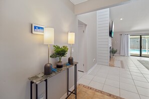 Un pasillo con una consola, dos lámparas de pared, una planta en maceta y un televisor de pantalla plana.