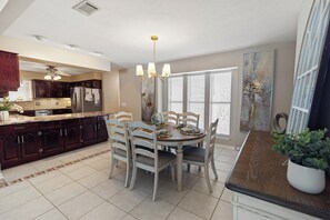 A modern kitchen with dark wood cabinets, a stainless steel refrigerator, and a dining area with a round table and chairs. - New Listing! Private Pool & Hot Tub! Near the Beach! (Panama City Beach)