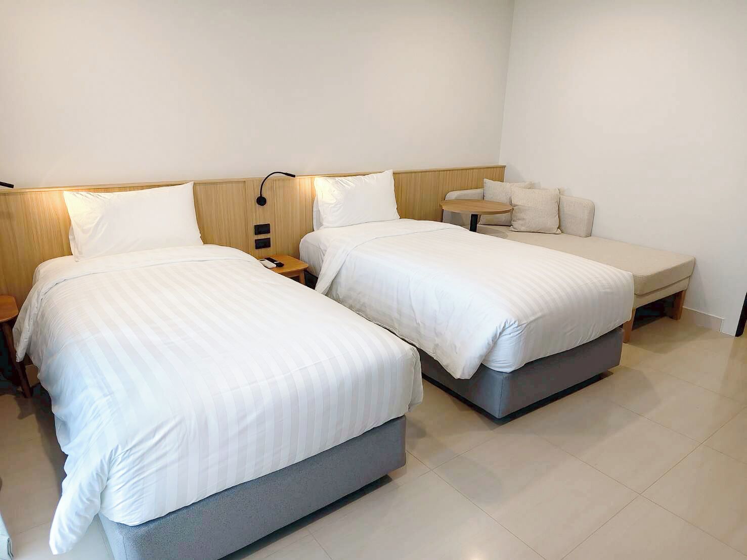Una camera d'albergo con due letti, un tavolino e un comodino.