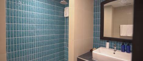 A bathroom with blue tiled walls, a white sink, and a mirror.