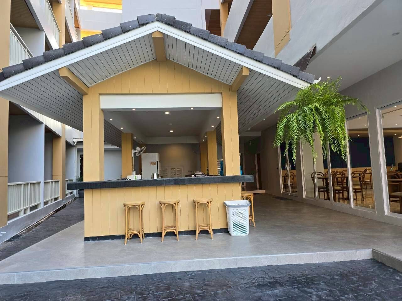 Zona de bar moderna en el interior, con mostrador, taburetes y un cubo de basura.