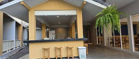 Zona de bar moderna en el interior, con mostrador, taburetes y un cubo de basura.