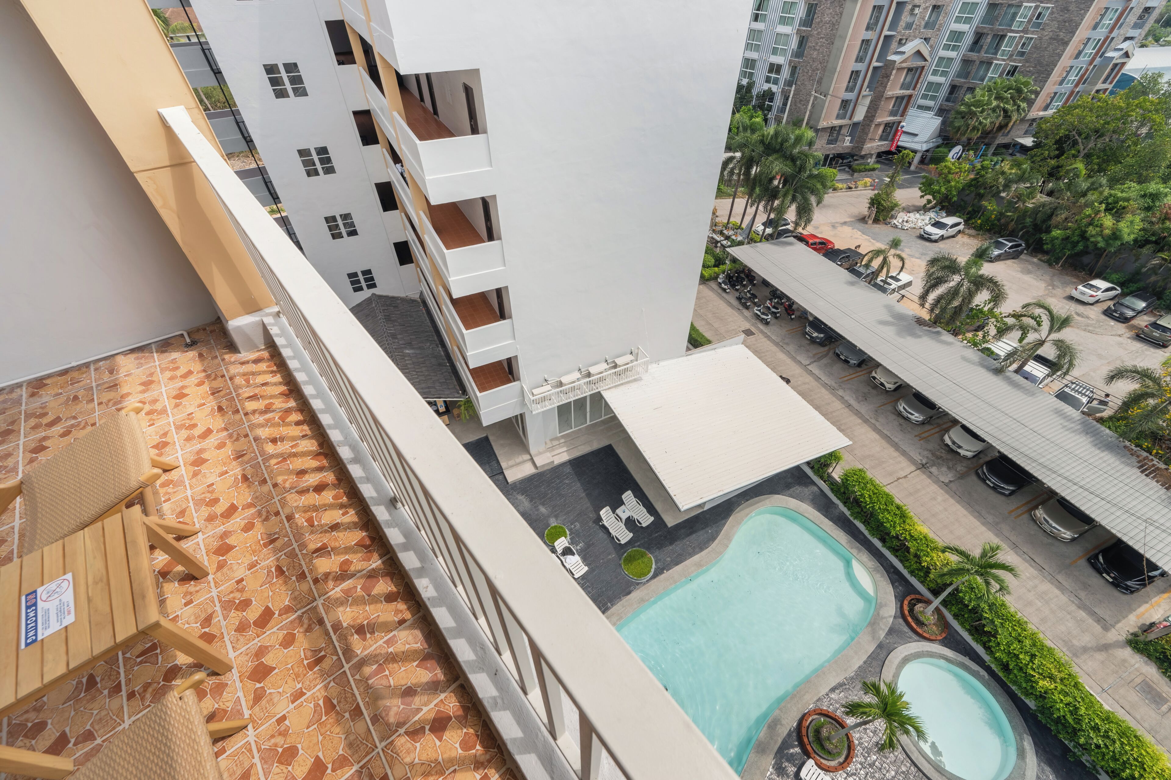 A high-rise building with a rooftop pool, outdoor seating, and a parking area.
