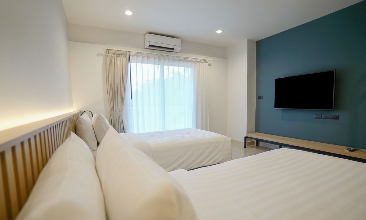 Una camera d'albergo con due letti, una TV a parete e un condizionatore.