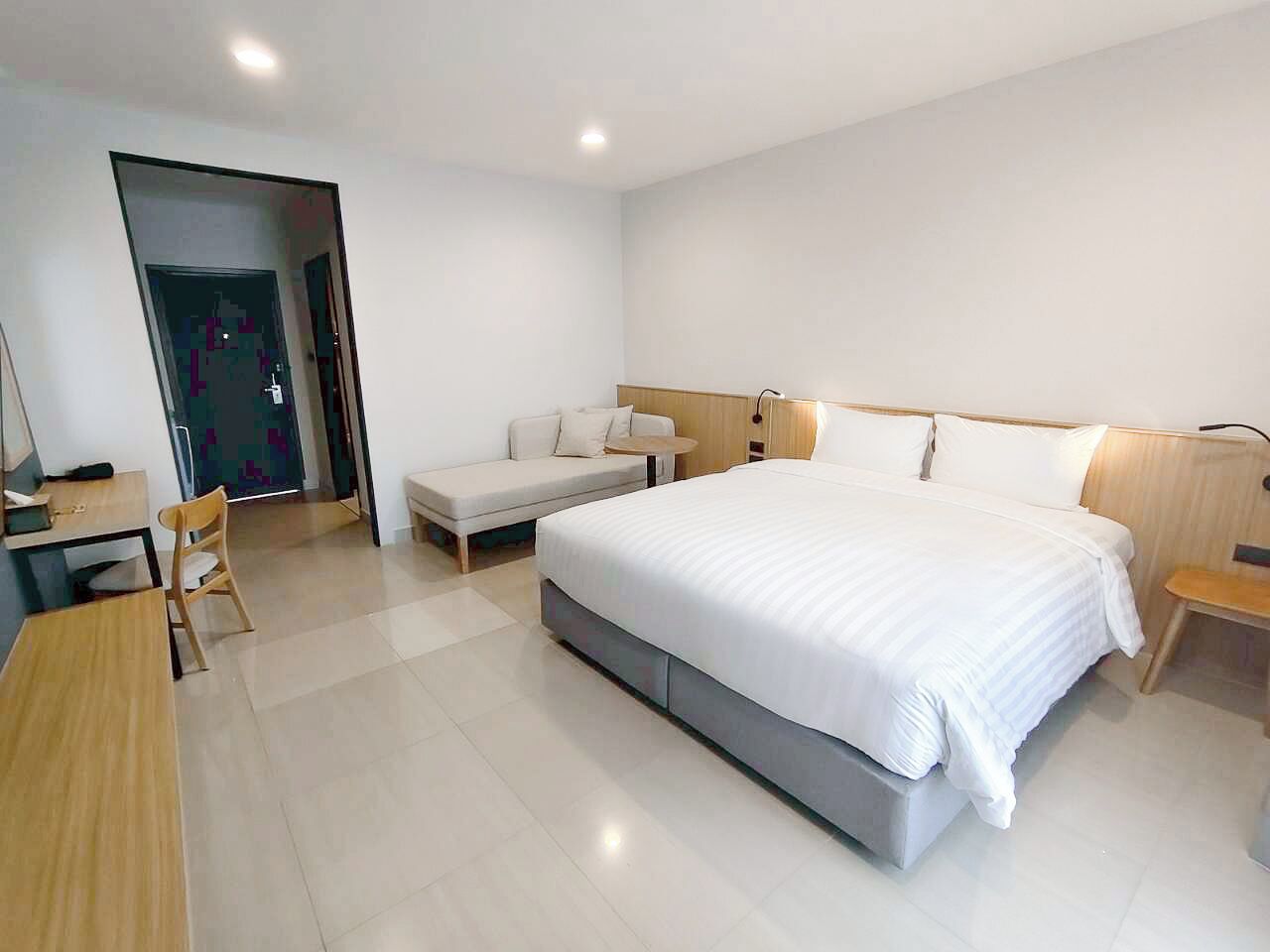 Une chambre d’hôtel moderne équipée d’un grand lit, d’un bureau, d’une chaise et d’un canapé.