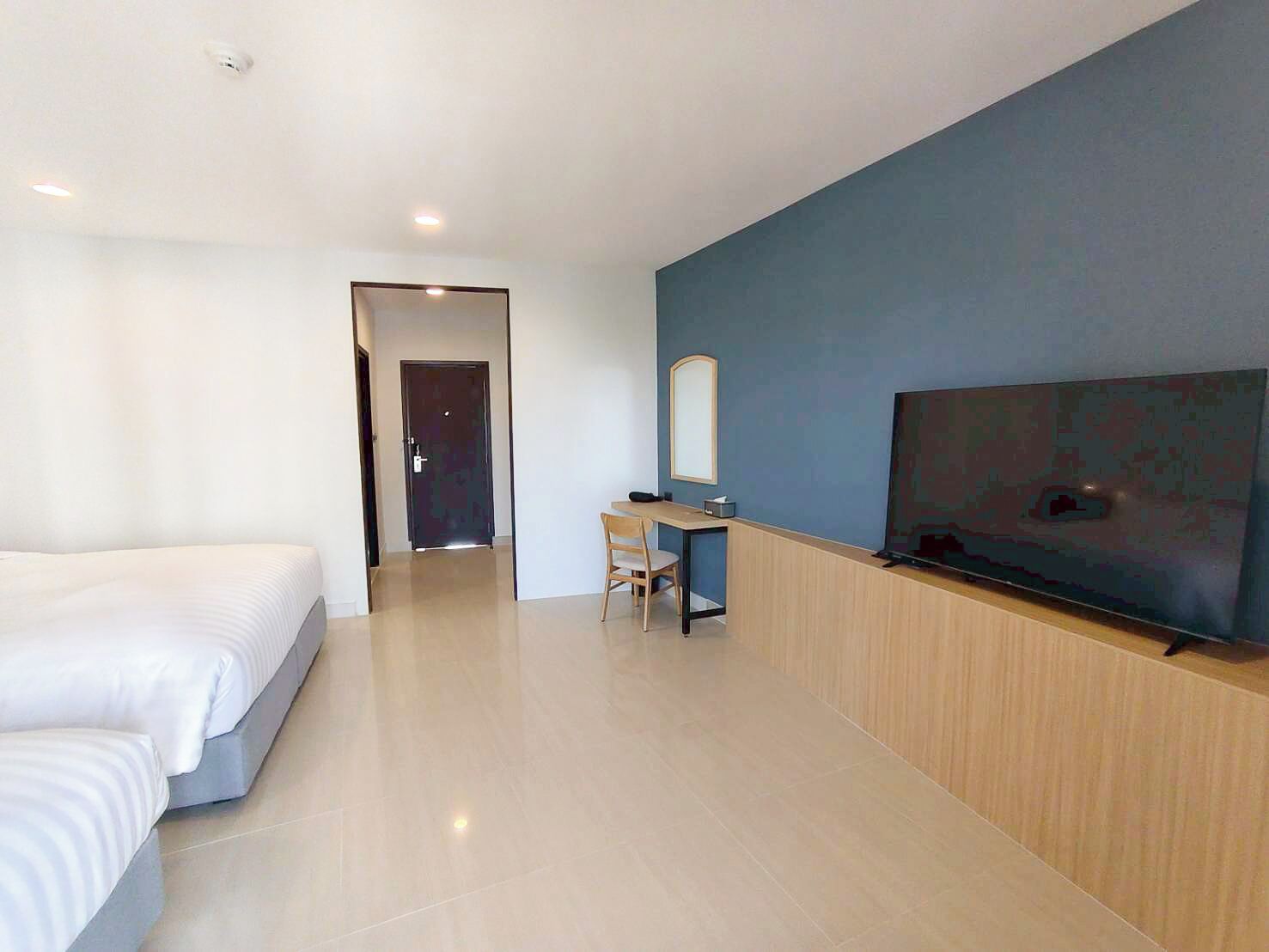 A hotel room with a bed, a desk, a chair, and a television.