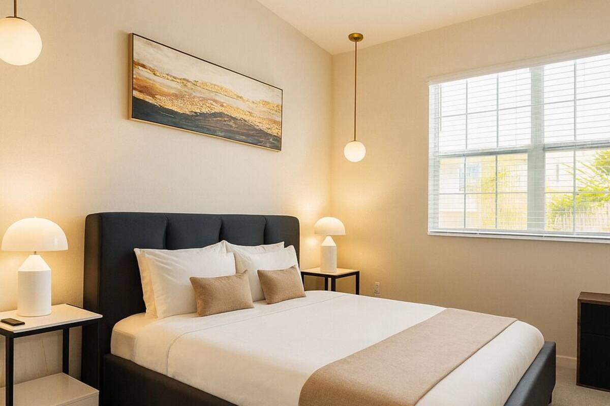 Una camera da letto moderna con un letto grande, due comodini, un'opera d'arte appesa al muro e una finestra con tende.