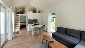 En modern inredning med ett matområde, en soffa, en trappa och ett kök.