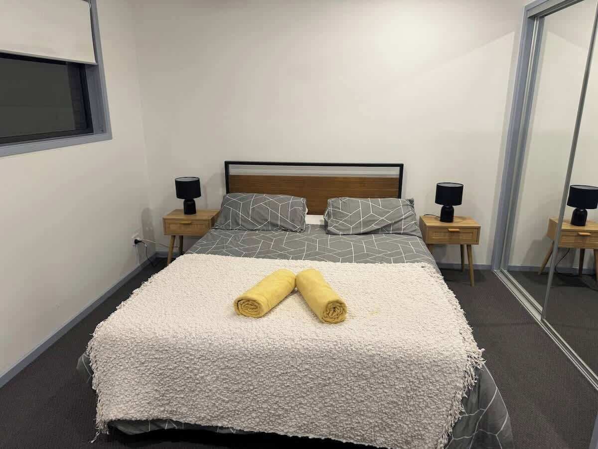 Quarto de hotel com uma cama, duas mesas de cabeceira com luminárias, um espelho grande e uma janela.