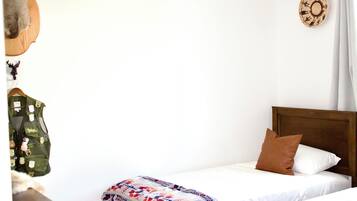 Un letto rifatto con cura, una coperta a fantasia, un cuscino marrone e una testiera in legno.