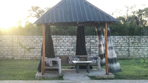 Um gazebo com telhado de metal, um banco e uma mesa.