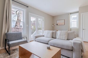 A modern living room with a grey sofa, a wooden coffee table, and a grey armchair. - Blueground | Riverside, washer, nr Charles River (Cambridge)