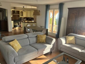 A modern living room with a sofa, a coffee table, and a dining area with a table and chairs. - Villa 6 + 2 with pool and air conditioning (LES ISSAMBRES)
