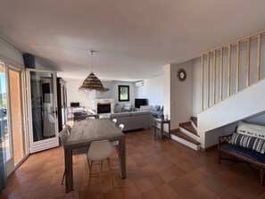 A modern interior with a dining area, sofa, TV, fireplace, and staircase. - Villa 6 + 2 with pool and air conditioning (LES ISSAMBRES)
