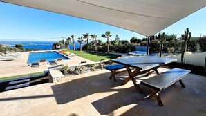 En uteplats med pool, utomhusmöbler och utsikt över havet.