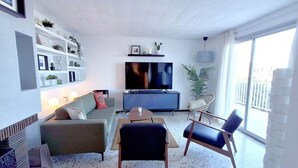 Ett modernt vardagsrum med en soffa, fåtöljer, en tv och en bokhylla.