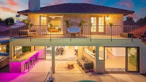 Een huis met twee verdiepingen, een balkon, buitenmeubilair en een zwembad.
