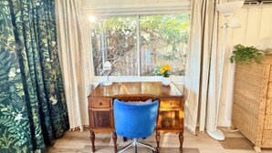 A room with a wooden desk, a blue chair, a window with curtains, and a wicker cabinet. - Quiet , 5 minutes to Tri-City Hospital,fast WiFi, blackout curtains, fenced yard (Vista)