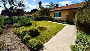 A residential property with a well-maintained lawn, a concrete pathway, and a house with a brown roof and yellow walls. - Quiet , 5 minutes to Tri-City Hospital,fast WiFi, blackout curtains, fenced yard (Vista)