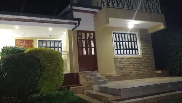 A two-story house with a balcony, a wooden door, and a window with bars. - Maya's Guest House (Nyeri)
