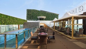 Una terraza en la azotea con piscina, zona de comedor y área de estar cubierta.