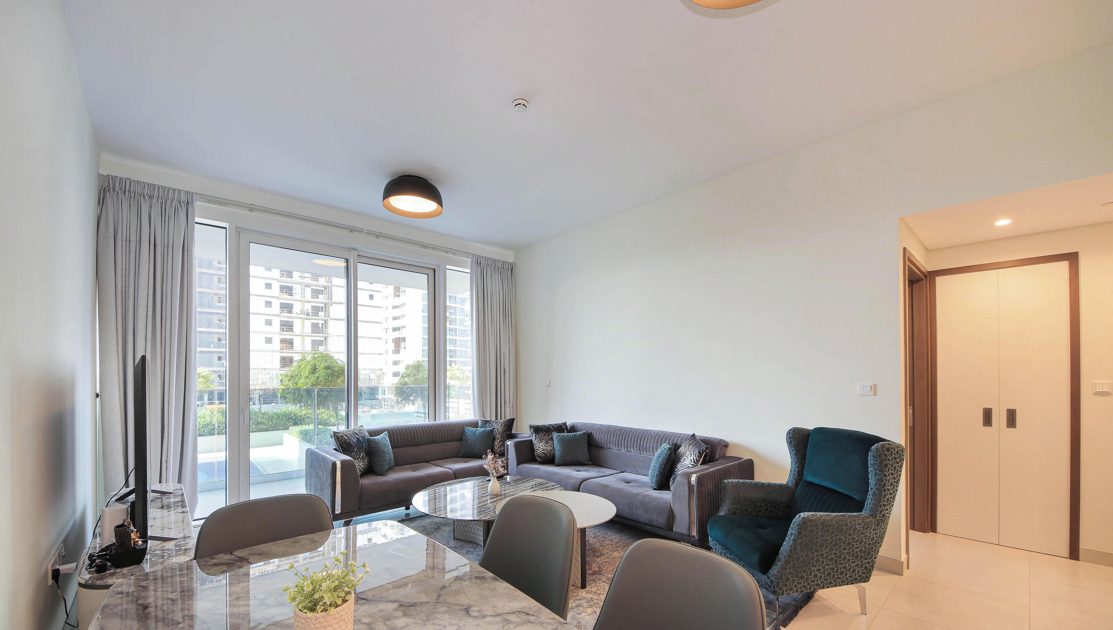 A modern living room with a sofa set, a glass coffee table, and a patterned armchair.