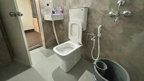 Een badkamer met een toilet, een bidet, een wastafel en een emmer.