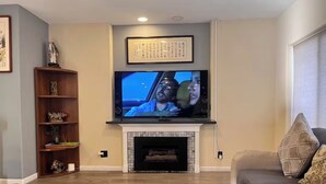 A living room with a fireplace, a television mounted above it, and a sofa. - Perfect 6-bedroom house with AC in welcoming Reno neighborhood (Reno)