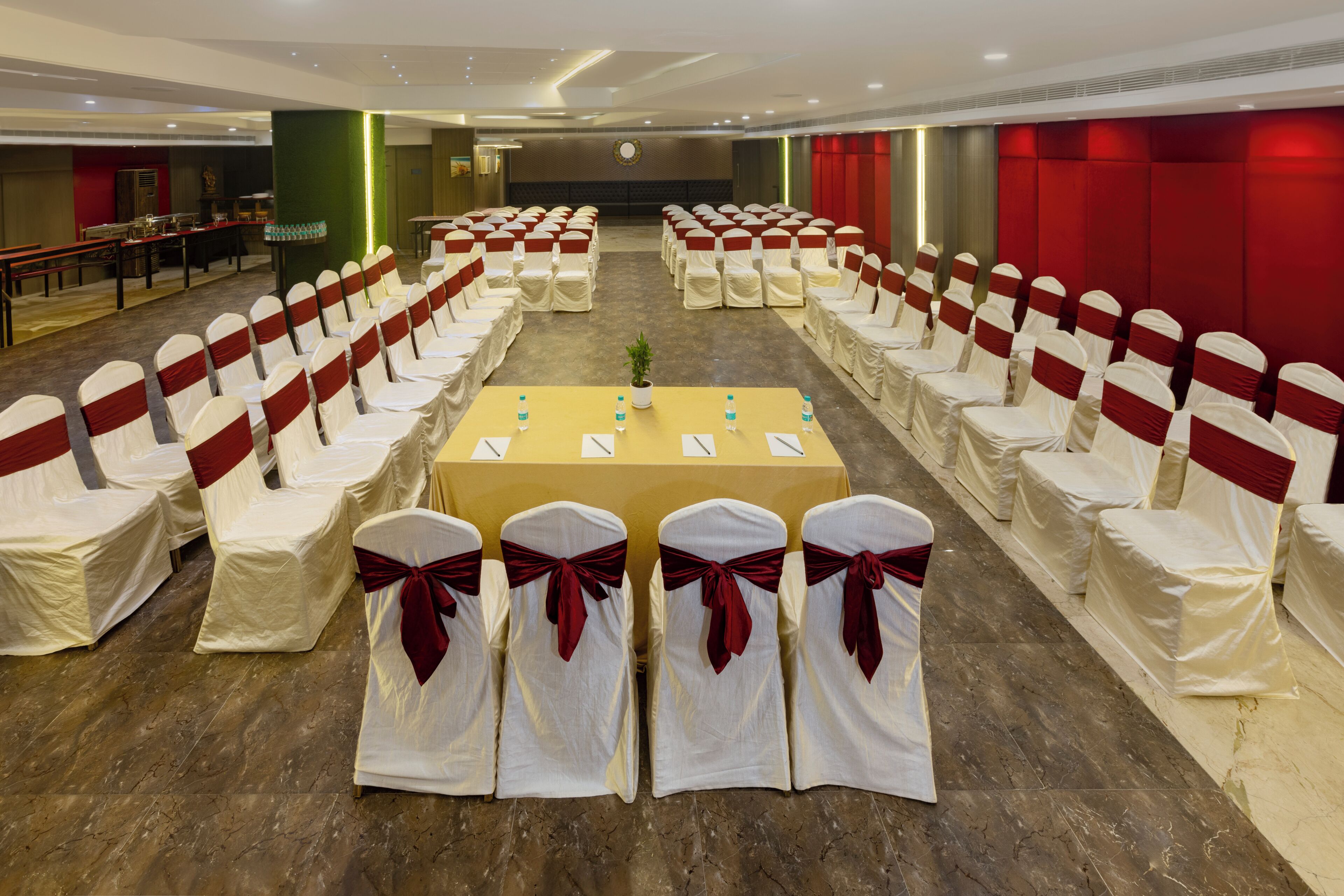 A conference room with rows of chairs, a long table, and a stage.