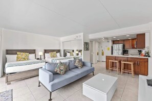 Ein modernes Hotelzimmer mit einem großen Bett, einer Couch, einem kleinen Tisch und einer Küchenzeile.