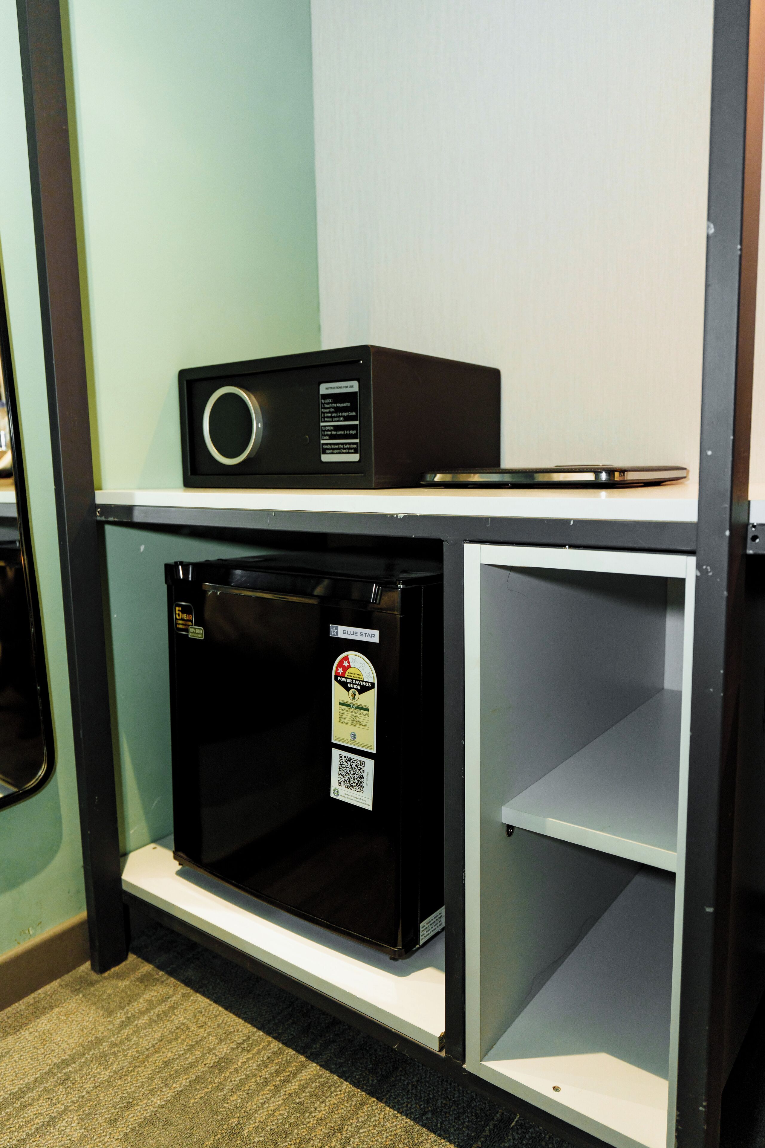 A compact kitchenette with a microwave, refrigerator, and a small shelf.