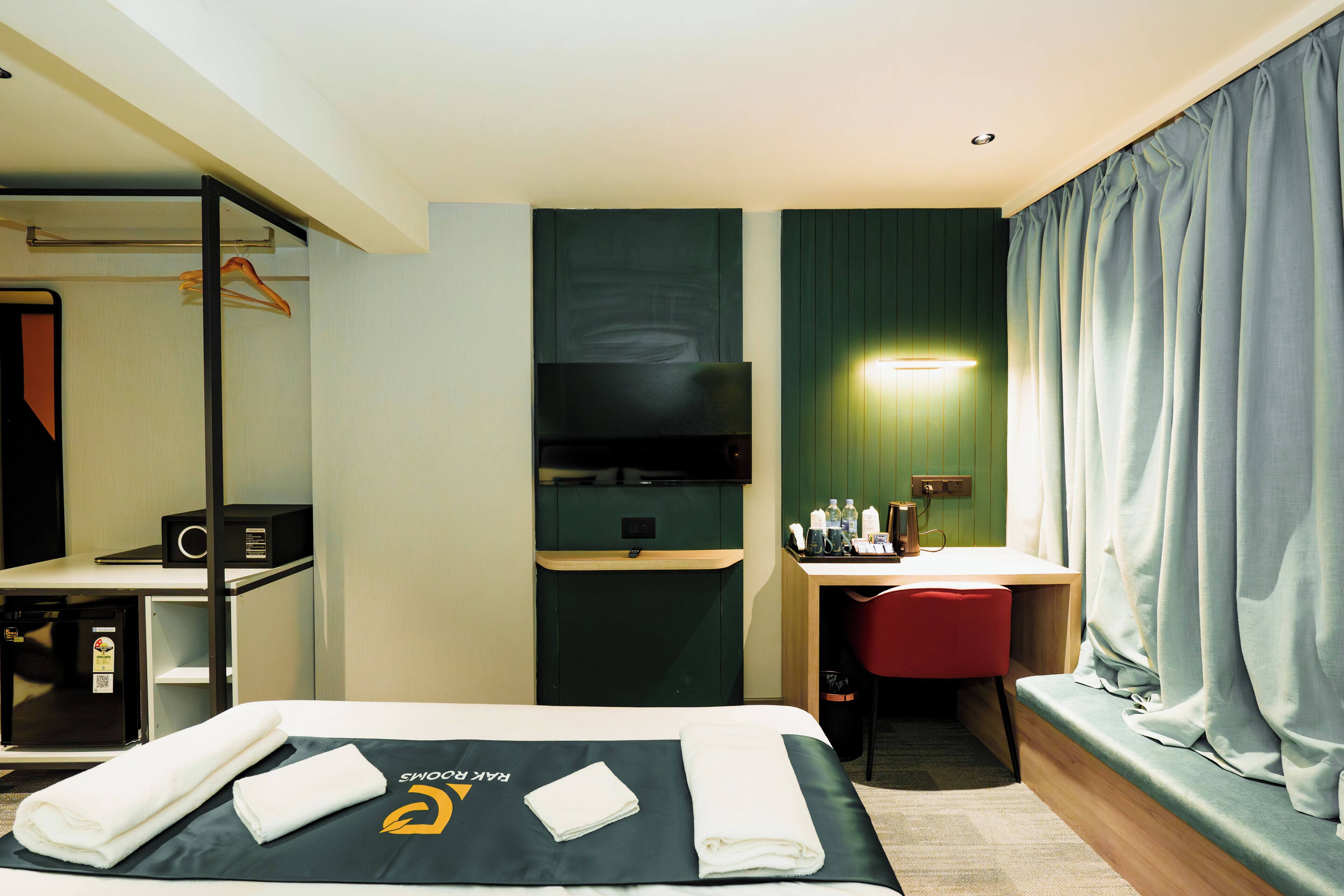 A hotel room with a bed, a desk, a TV, and a seating area.
