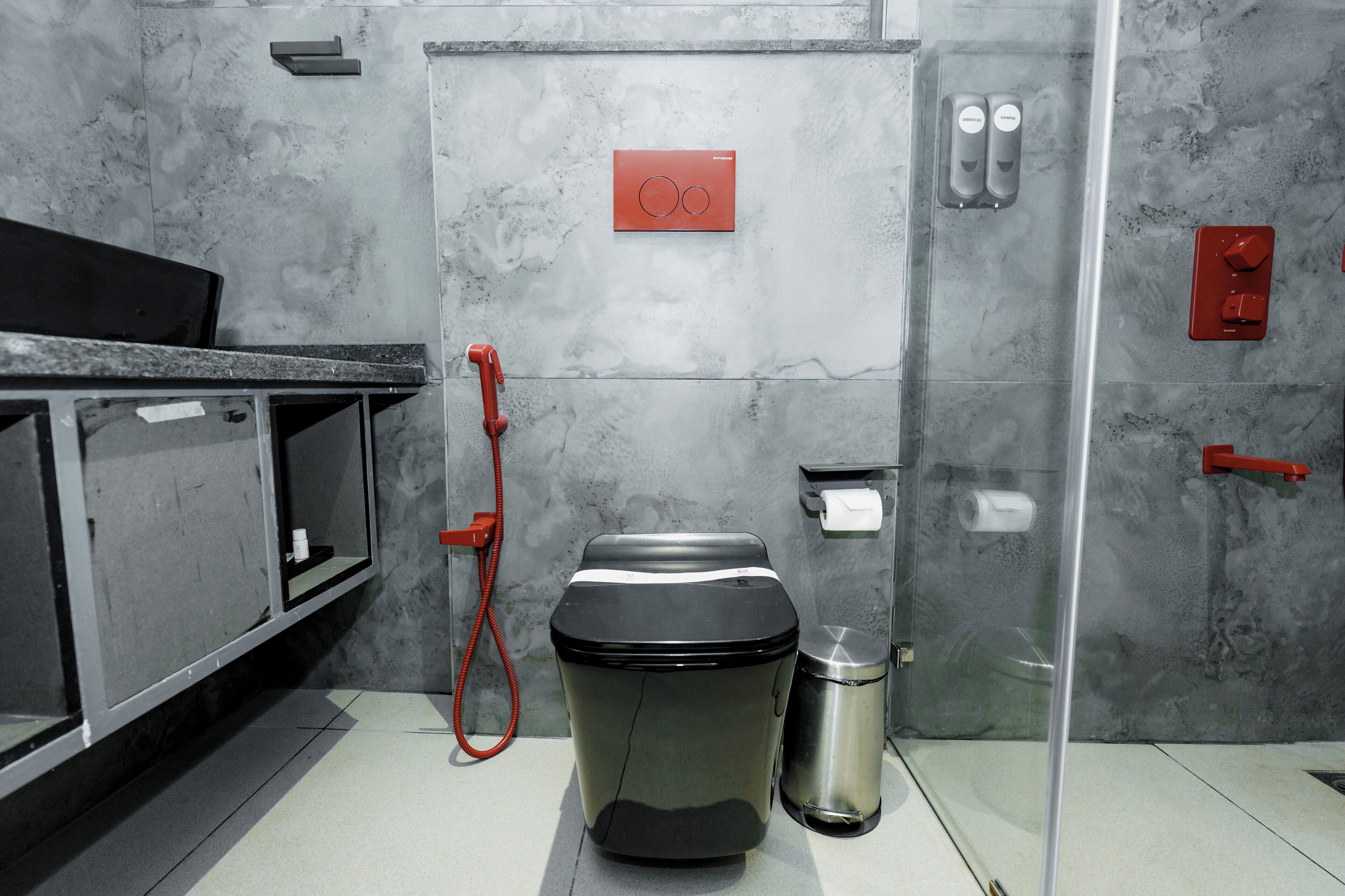A compact bathroom with a toilet, bidet, and trash can.