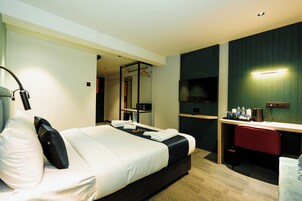 Una habitación de hotel con cama, mesita de noche, escritorio, silla y espejo.