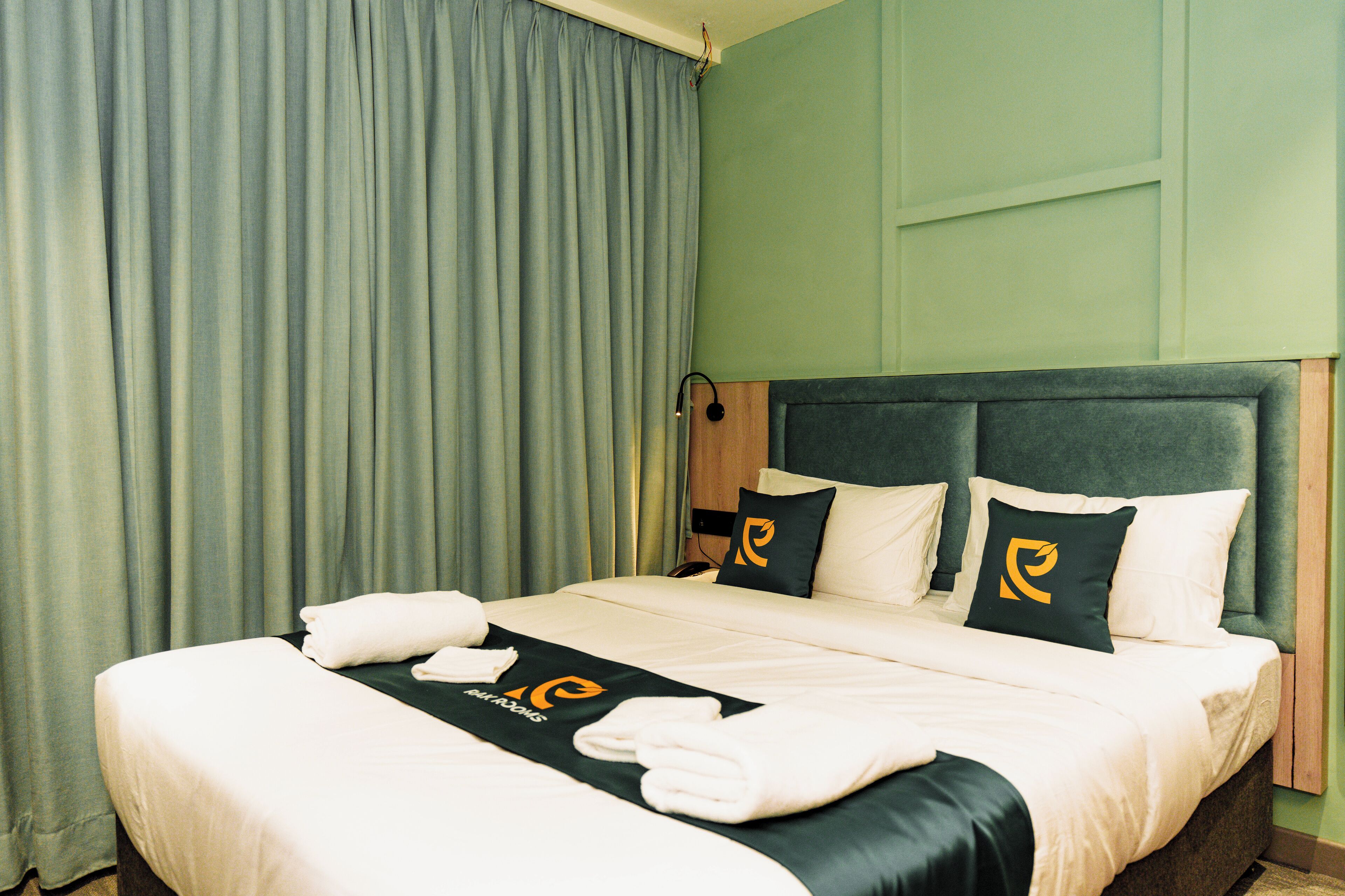 Una cama bien hecha con una colcha blanco y negro, dos almohadas con un logotipo y una toalla al lado.