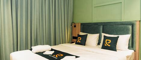 Una cama bien hecha con una colcha blanco y negro, dos almohadas con un logotipo y una toalla al lado.