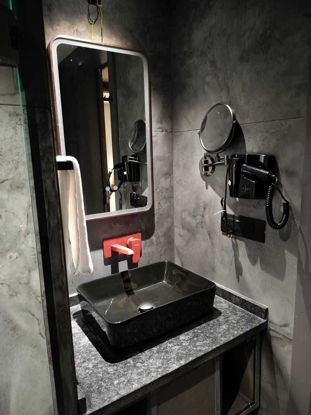 A bathroom with a rectangular sink, a mirror, and a telephone.