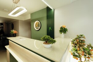 Un mostrador de recepción con un logotipo, una planta en maceta y un cartel en la pared.