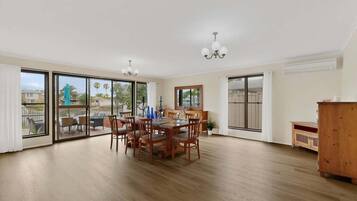 A spacious dining area with a wooden table and chairs, large sliding glass doors leading to an outdoor patio, and a wooden cabinet.